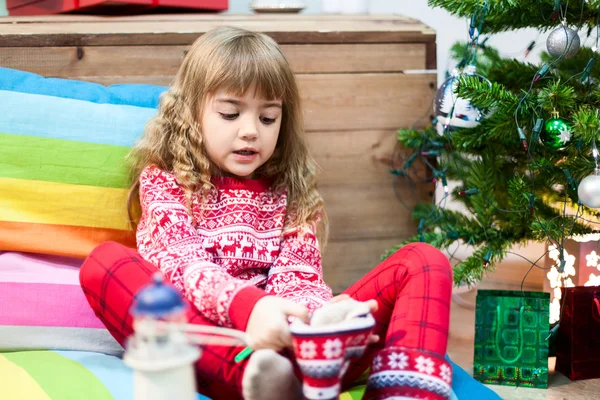 赤い毛皮のブーツを身に着けている小さな女の子クリスマスの装飾 緑の木と国内の部屋 — ストック写真