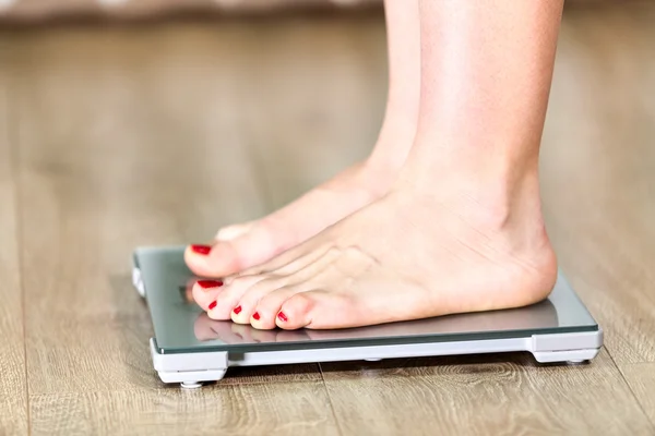 Close-up of Caucasian woman with bare feet is on floor weight scales