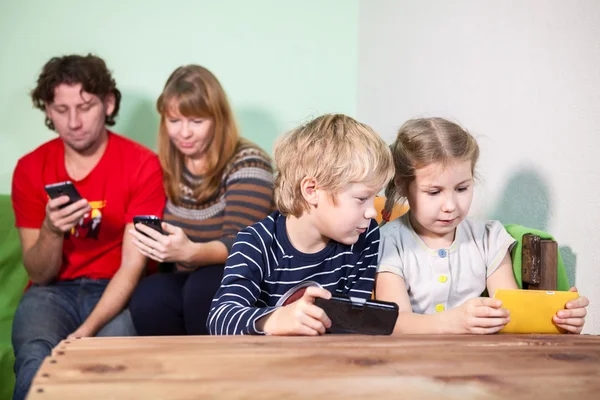 Ailesi Aletlerle Oturan Akıllı Telefonlarla Oyun Oynayan Çocuklar — Stok fotoğraf