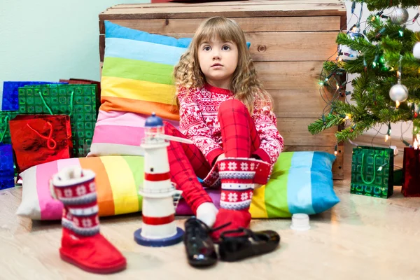 小さな白人の女の子で国内の部屋でクリスマスツリーと床の上の色枕 — ストック写真