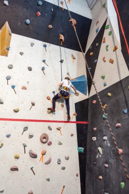 Güvenlik halatıyla duvara tırmanan küçük beyaz bir kız.