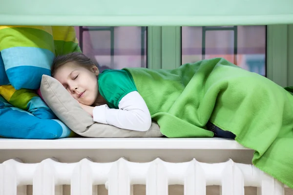 年轻的白人女孩睡在暖气散热器上方的塑料窗台上 — 图库照片