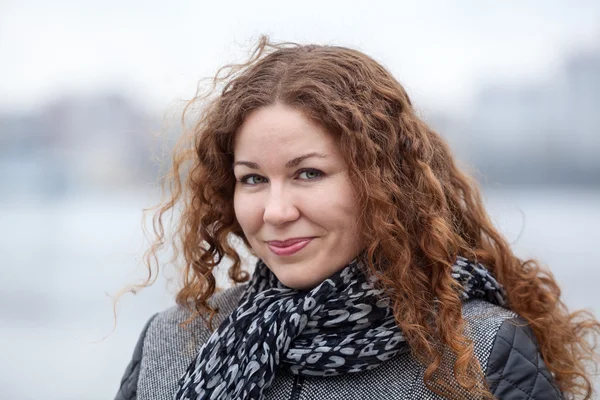 Mujer bastante caucásica con pelo rizado largo en el viento, cabeza y hombros retrato — Foto de Stock