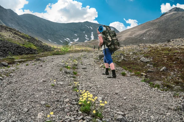 Donna escursionista con zaino segue il gruppo principale scalando la strada di montagna — Foto Stock