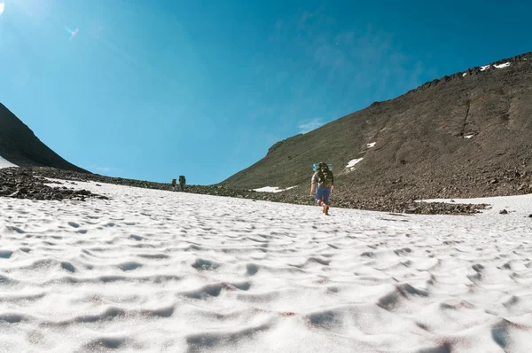 Equipo de escaladores escalando montaña pasan uno al otro en la nieve, vista trasera —  Fotos de Stock