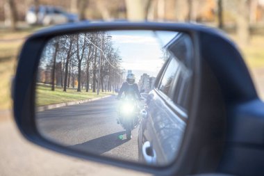 Bir arabanın dikiz aynasında motosiklet sürerken çıkan göz kamaştırıcı ışık. Göz kamaştırıcı etki konsepti