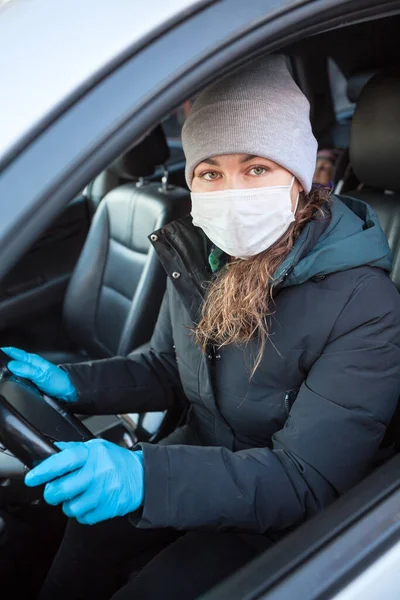 青い保護手袋と車を運転する準備ができて安全マスクの女性ドライバー Covid 19中の個々の予防措置 — ストック写真