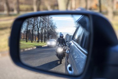 Karşılıklı geçiş, göz kamaştırıcı ışıklandırmalı motosiklet ve araç arabayı solluyor, yan aynaya bakıyor. Uygunsuz sürüş veya trafik ihlali