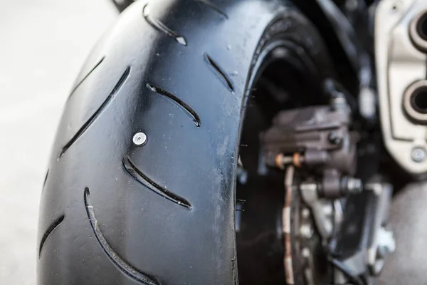 Puncture of rear wheel of motorcycle, steel screw is in tyre, a horizontal image