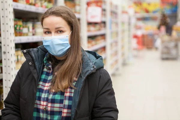 医療用マスクを身に着けている白人女性の肖像 ハイパーマーケットに立って 暖かい服 コピースペース — ストック写真