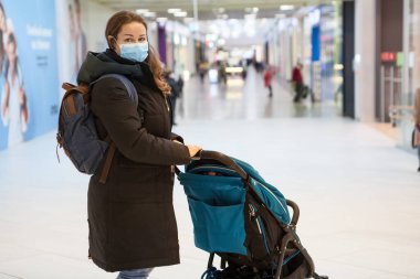 Alışveriş merkezinde küçük bir çocukla yürürken güvenlik maskesi takan yetişkin kadın portresi