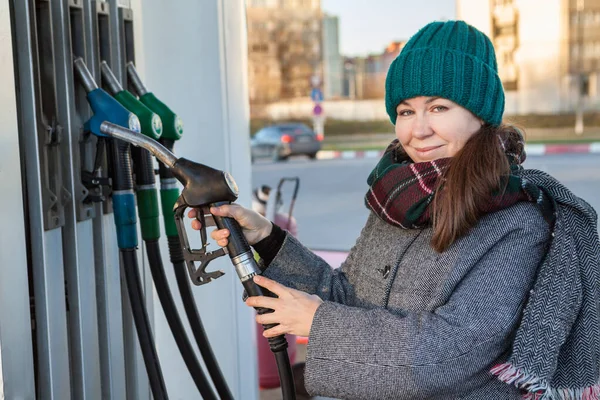 Ellerinde Gaz Hortumuyla Benzin Istasyonunda Soğuk Mevsimde Kameraya Bakan Kadın — Stok fotoğraf