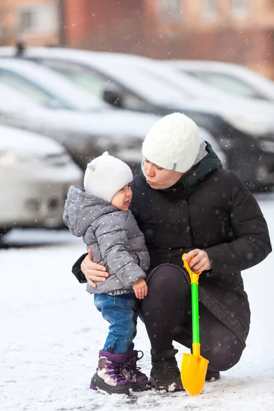 母亲在雪地的街道上让哭哭啼啼的幼儿安静下来 拥抱和亲吻着儿子 — 图库照片