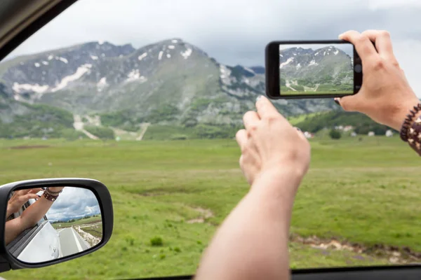 汽车的乘客通过车窗拍照时 手伸进车窗 在山中绊倒 注意力集中在侧镜上 — 图库照片