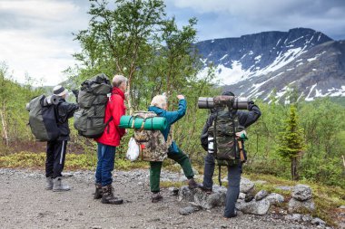 Yürüyüş rotalarına başlamadan önce dağların zirvesine bakan bir grup dağcı, tek bir aileyle dağlarda dağcılık yapıyorlar.