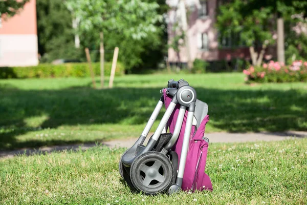 Katlanmış Bebek Koltuğu Yaz Güneşli Parkta Yeşil Çayırda Bebek Arabası - Stok İmaj