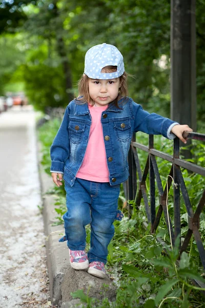 Little Caucasian Meisje Dragen Jeans Pet Lopen Langs Stalen Hek — Stockfoto