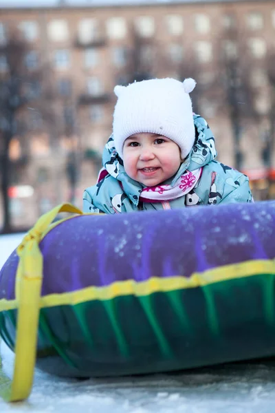 在雪地的斜坡上滑行 带着雪地管微笑着快乐的婴儿 白人儿童 — 图库照片