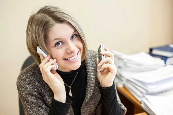 Frau telefoniert mit zwei Telefonen — Stockfoto