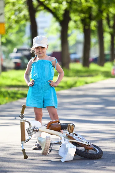 Niña de pie junto a una bicicleta — Foto de Stock