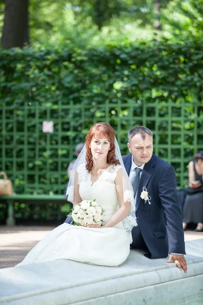 Wedding couple sitting near fountain — Stock Photo, Image