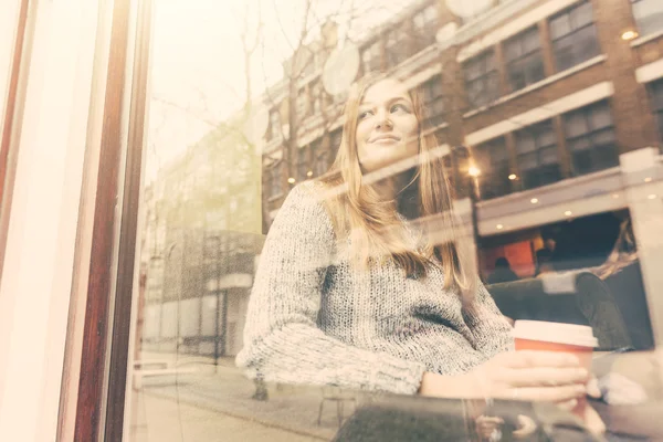 Hermosa mujer en un café visto a través de la ventana — Foto de Stock