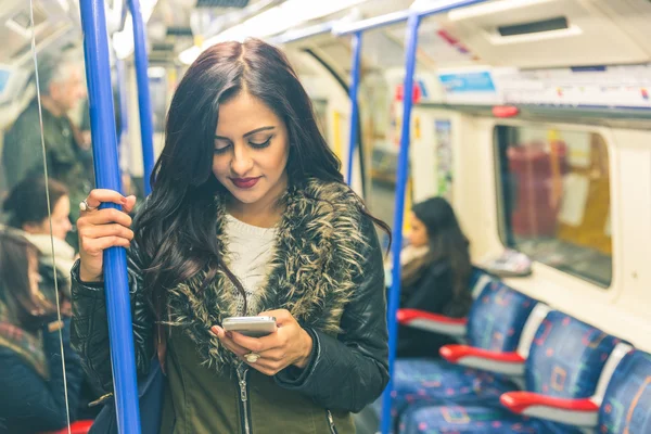 Jonge Indiase vrouw met behulp van slimme telefoon in de buis — Stockfoto