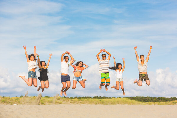 Multiracial group of friends jumping on the beach