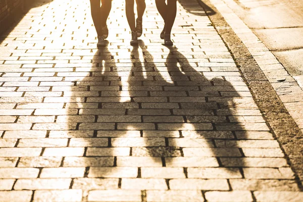 Skuggor av tre tjejer som går på en trottoar i staden — Stockfoto