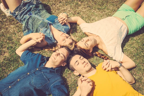 Amigos mentindo e relaxando na grama — Fotografia de Stock