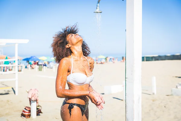 Giovane donna nera che fa una doccia in spiaggia — Foto Stock