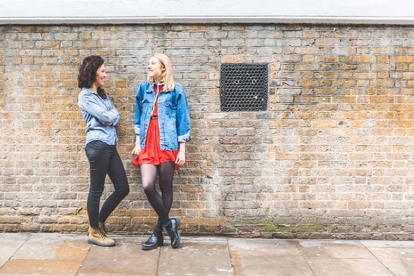 Dos mujeres apoyadas en una pared y hablando en Londres — Foto de Stock