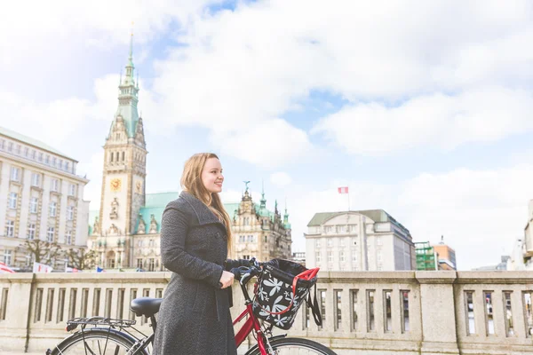 Mujer joven caminando y sosteniendo una bicicleta en Hamburgo — Foto de Stock