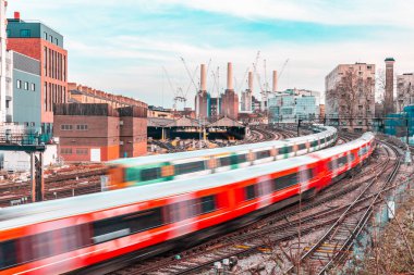 Londra 'daki raylardaki ve elektrik santralindeki trenler - hareket halindeki trenler ve bir sonraki yoğun istasyon - binalar ve inşaat halindeki şehir arka planı - seyahat ve ulaşım kavramları