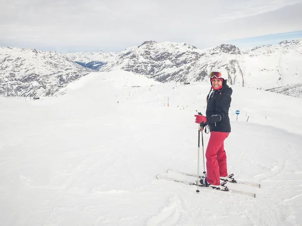 Happy woman with ski on top of mountain slopes - Beautiful young woman enjoying ski holidays and having fun on the snow on a beautiful sunny winter day in Livigno - Sport and travel concepts