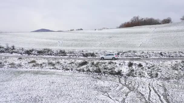 雪の田舎道を運転する車の空中トップビュー 白い田舎とイタリアの冬のシーンの空中ビデオ 旅行と自然の概念 — ストック動画