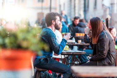Stockholm 'ün eski kasabasında kahve içen hippi arkadaşlar, açık havada oturup eğlenen genç bir çift.