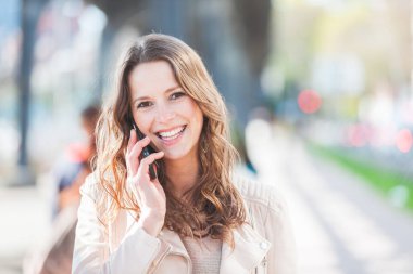 Hamburg 'da telefonla konuşan güzel bir genç kadının portresi yirmili yaşlarının başında, esmer, uzun saçlı, kameraya bakan ve gülümseyen bir kadın.