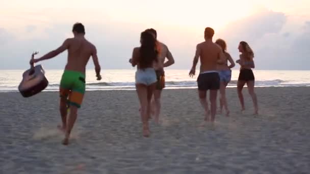 Emberek csoportja fut a tengerparton felé a tenger - Fiatal barátok együtt a tengerparton élvezik az időt együtt naplementekor - Életmód és barátság fogalmak — Stock videók