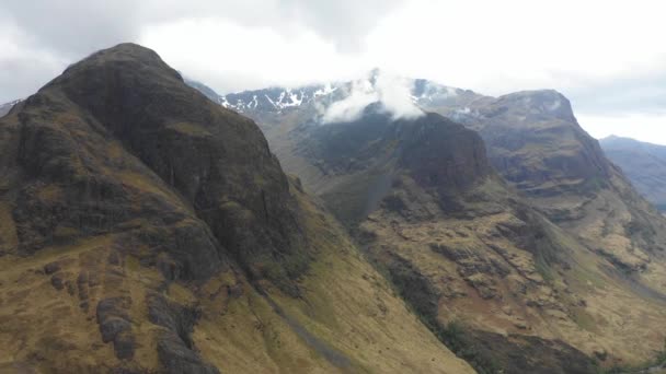 Aerial view of  highlands in Scotland, with clouds over the famous mountains known as Three Sisters of Glencoe - Moody weather in Scottish highlands - Background ready image of beautiful landscape — Stock Video