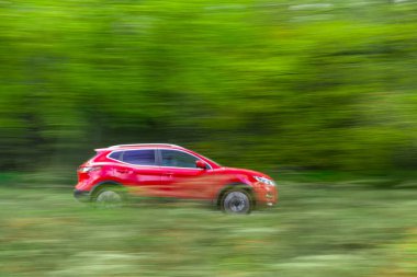 Çevre dostu otomobil yeşil ağaçların arasından geçiyor, çevreci görüş - Bulanık ormanın yan tarafında görülen hızlı kırmızı çevre dostu araç - çevre dostu ulaşım ve çevre kavramı