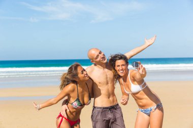 Mutlu çok ırklı arkadaşlar sahilde selfie çekiyorlar, çok ırklı insanlar, güneşli Fuerteventura 'da birlikte eğleniyorlar.