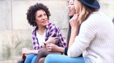 Şehirde akıllı bir telefona bakan mutlu çok ırklı kadınlar.