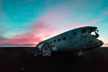 İzlanda, günbatımında Solheimasandur 'da uçak enkazı - eski ve terk edilmiş bir uçak, alacakaranlıkta, siyah plaja çakıldı, etrafta kimse yoktu - seyahat ve ulaşım kavramları