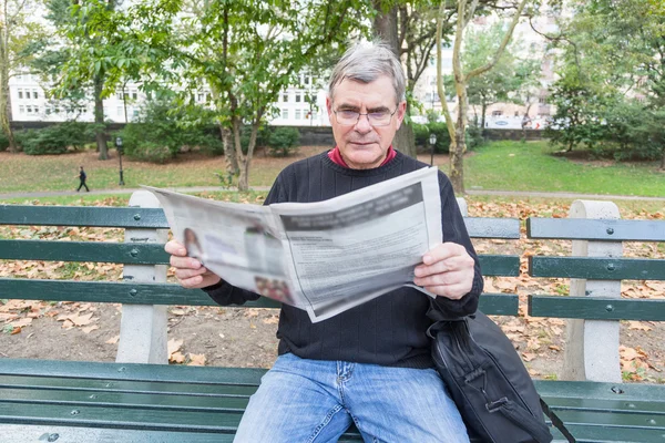 Homme âgé lisant un journal au parc — Photo