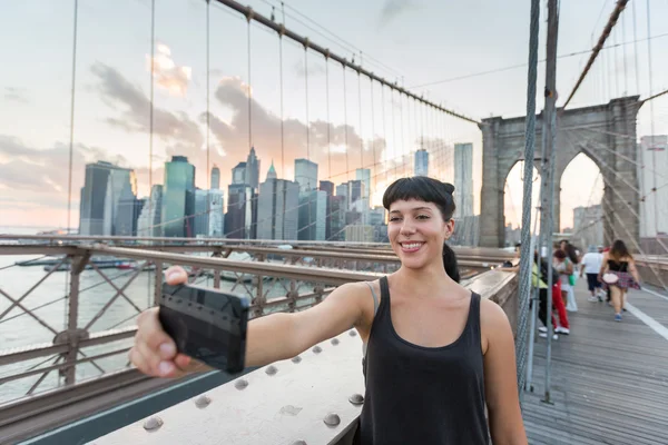 Hübsche junge Frau macht Selfie auf brooklyn bridge — Stockfoto