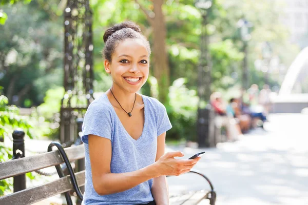 Bella razza mista giovane donna digitando sul telefono cellulare — Foto Stock