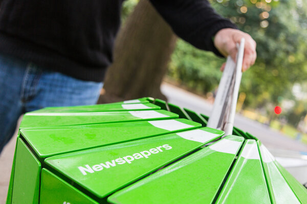 Man Wasting Newspaper in Recycling Basket