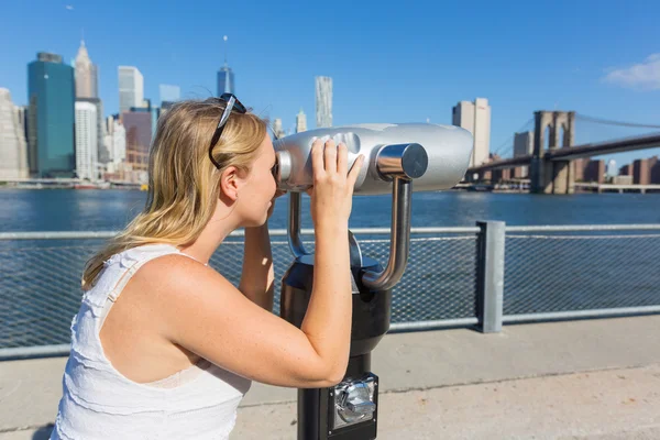 Vrouw die door een verrekijker kijkt — Stockfoto