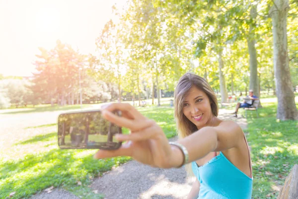 Bela jovem mulher tomando selfie no parque — Fotografia de Stock